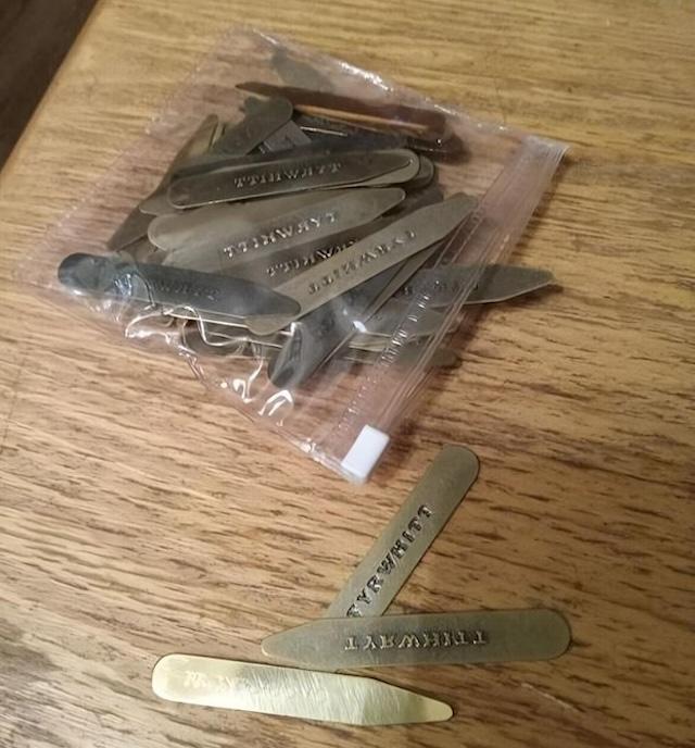 A pile of vintage collar stays, carefully stored in a small plastic bag. Each stay is stamped with "TURNWIT."